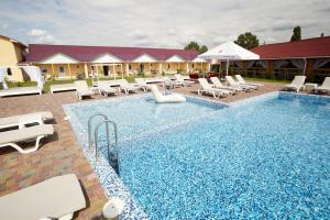 a swimming pool with lounge chairs and a hotel at Райский Дворик in Pogreby