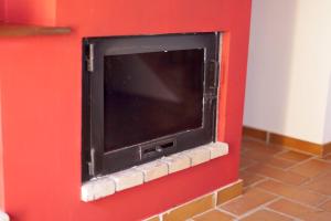 - une télévision sur un mur rouge dans l'établissement La Quintana de Somao, Casa de Arriba, à Pravia