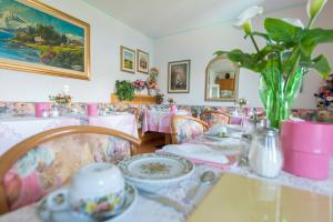 una sala da pranzo con tavoli e sedie rosa e un vaso di fiori di Casa Alessandra a Malcesine