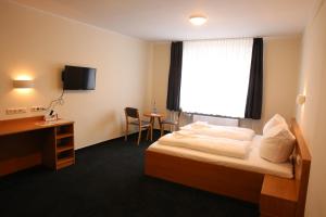 マクデブルクにあるCity-Pension Magdeburgのベッド、デスク、窓が備わるホテルルームです。