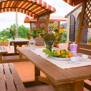 a wooden picnic table with a bowl of fruit on it at La Mariola Apartments in Santa Luce