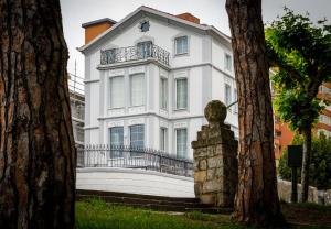 a white house with a statue in front of it at Suite Home Pinares in Santander