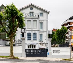 a white house with a tree in front of it at Suite Home Pinares in Santander