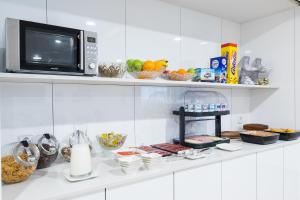a kitchen with a microwave and some food on a shelf at Suite Home Pinares in Santander