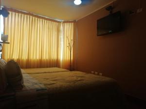 a bedroom with a bed and a window with a television at Hospedaje Oasis in Chiclayo