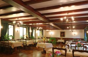 een eetkamer met tafels en stoelen en kroonluchters bij Auberge De La Foret - Logis in Vendenheim