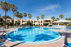 a large swimming pool with palm trees and buildings at Tagoro Park in Costa Del Silencio