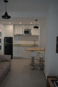 a kitchen with a couch and a table with stools at Apartamento Playa Victoria - Cádiz in Cádiz