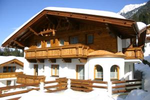 una gran casa de madera con nieve en el techo en Appartements Michaela, en Neustift im Stubaital