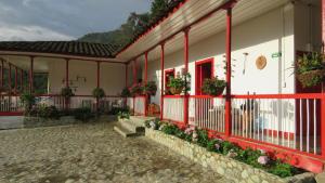 ein Gebäude mit roten Zierleisten und Blumen im Innenhof in der Unterkunft La Cabaña Ecohotel - Valle del Cocora in Salento