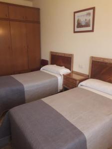 Báscara的住宿－Pensio Fluvia，酒店客房设有两张床和橱柜。