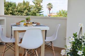 a dining room table with white chairs in front of a window at Centurio luxury rooms in Tropea