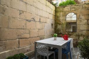 バースにあるCeres Newly refurbished 3 bedroom in Heart of Bathの煉瓦の壁の横に座るテーブルと椅子