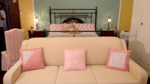 kanapa z różowymi poduszkami w salonie w obiekcie B&B Le Rose w mieście Siderno Marina