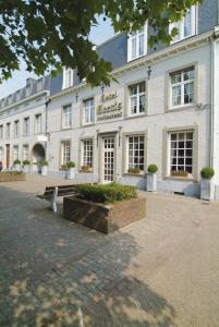 a white building with a bench in front of it at Hotel Geerts in Westerlo