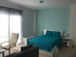 ein Schlafzimmer mit einem blauen Bett und einem Stuhl in der Unterkunft Calle Ollerias in Málaga