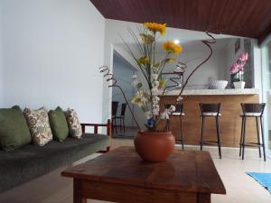 eine Vase mit Blumen auf einem Tisch im Wohnzimmer in der Unterkunft Pouso Gloria in São João Batista do Glória