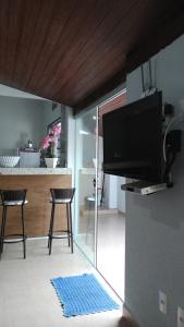 a living room with a tv and a kitchen at Pouso Gloria in São João Batista do Glória