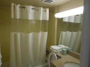 a bathroom with a white shower curtain and a sink at Belmont Inn & Suites Virginia Beach in Virginia Beach