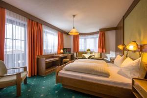 a hotel room with a large bed and a desk at Alte Post in Ellmau