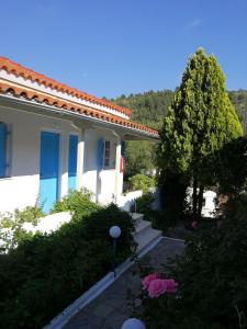 uma casa branca com uma porta azul e uma árvore em Blue White House em Kalamitsi