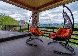 two swing chairs on a porch with a view at Hotel GoodAura in Gudauri