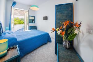 a blue bedroom with a bed and a vase of flowers at Bristol Hotel in Ischia +37 photos