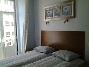 リスボンにあるBaixainnのベッドルーム1室(木製ヘッドボードと窓付)