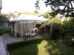 a patio with a table and an umbrella in a garden at Family Hotel Bellehouse in Chernomorets