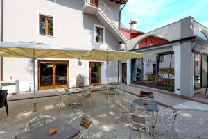 eine Terrasse mit Tischen, Stühlen und einem Sonnenschirm in der Unterkunft B&B La Contessa in Monfalcone