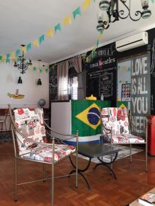 una stanza con due sedie e un tavolo con una bandiera di Casa Beatles Hostel Bauru a Bauru