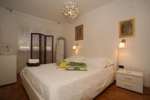 Un dormitorio con una gran cama blanca y una lámpara de araña. en Domus Apartments, en Trogir