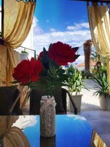 a vase with red flowers sitting on a table at Apartment Lovre in Split