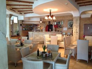 a restaurant with tables and chairs and a bar at Kamelot Hotel in Pasarel