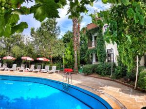 una piscina con sillas y sombrillas frente a una casa en Erciyes Apart Hotel, en Fethiye