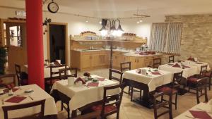 ein Restaurant mit weißen Tischen und Stühlen sowie einer Küche in der Unterkunft Chalet Campiglio Imperiale Garnì in Madonna di Campiglio