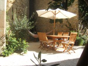 une table et des chaises en bois avec un parasol dans l'établissement Gite la Tour, à Pépieux