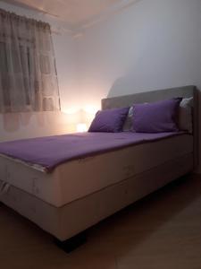 a bed with purple pillows in a room at Porodični in Sveti Stefan