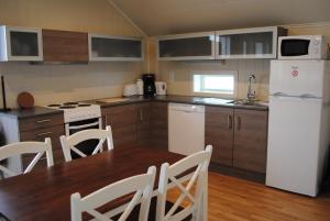 uma cozinha com uma mesa e um frigorífico branco em Furoy Fishingcamp and Hotel Apartments em Sorreisa