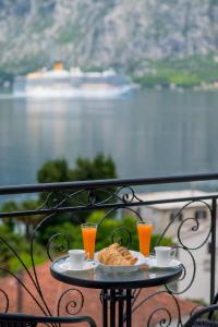 een tafel met een bord eten en twee glazen sinaasappelsap bij StOliva RESIDENCE with infinity pool in Kotor