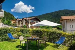 a table with chairs and an umbrella in the grass at Appartamenti Residenza Pineta in Molveno