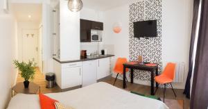 ein Schlafzimmer mit einem Bett und eine Küche mit orangefarbenen Stühlen in der Unterkunft Studio Sympa Ramblas Centre Toulouse in Toulouse