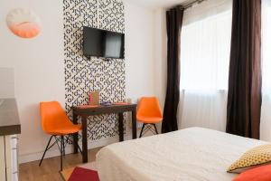 トゥールーズにあるStudio Sympa Ramblas Centre Toulouseのベッドルーム(オレンジ色の椅子、テーブル、テレビ付)