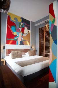 a bedroom with a bed with a painting on the wall at Boutique Hotel Saint-Géry in Brussels