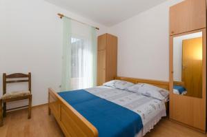 a bedroom with a bed and a chair and a window at Apartments Caric in Ivan Dolac