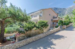 a house with a stone wall next to a street at Apartments Caric in Ivan Dolac