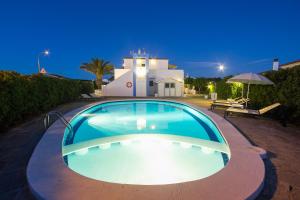 a swimming pool in front of a house at night at Nuvolet Apartaments in Cala en Blanes