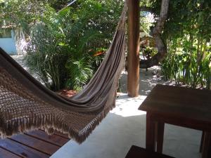 a hammock in a patio with a table and plants at Canto do Sabiá Caraíva in Caraíva