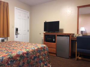 a hotel room with a bed and a flat screen tv at Evergreen Lodge in Mount Shasta