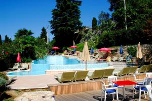 uma piscina com cadeiras, mesas e guarda-sóis em Ambienthotel Spiaggia em Malcesine